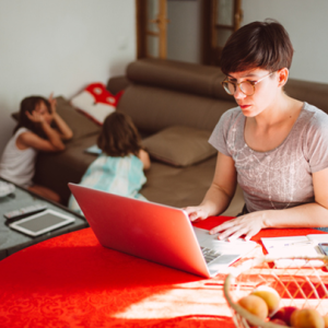 Mother using a laptop with children in the background