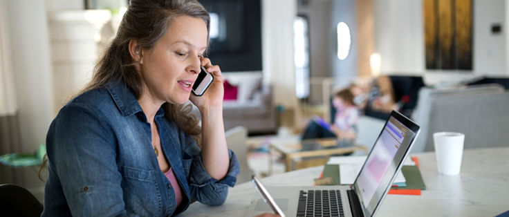 Woman calling on the phone in front of her laptop