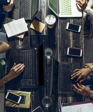 group around a table using a laptop and phone