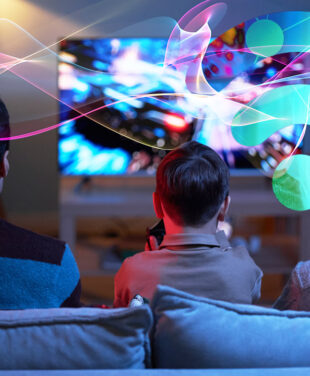 Rear view of child sitting on sofa with his parents and playing video game